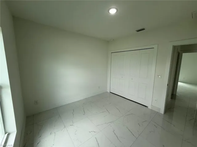 Unfurnished bedroom featuring light marble finish floors, a closet, and recessed lighting