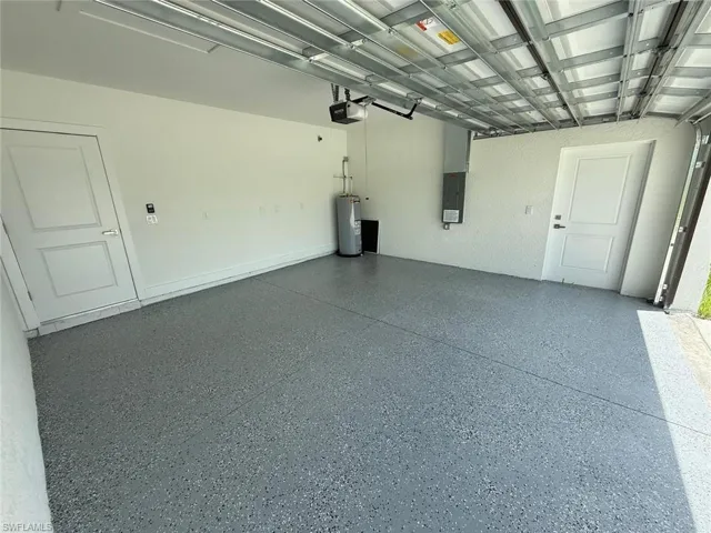 Garage featuring electric panel, gas water heater, and a garage door opener