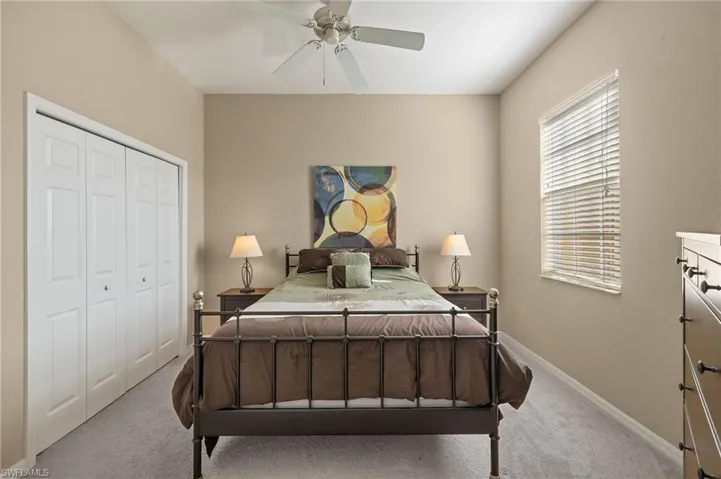 Bedroom with light carpet, ceiling fan, and a closet