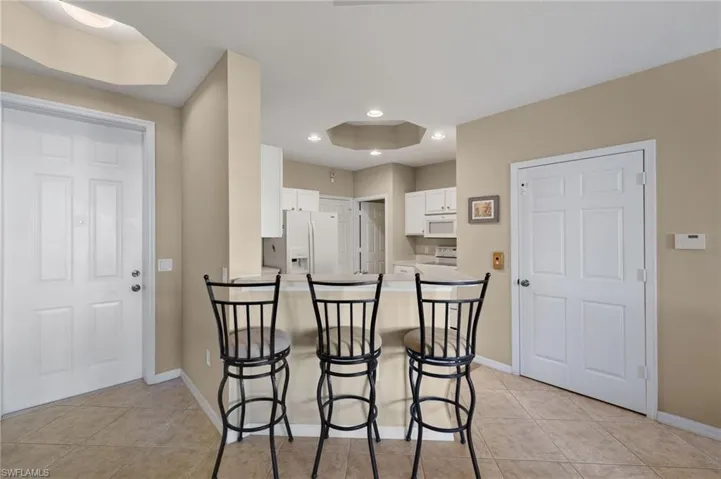 Kitchen with white appliances, a kitchen bar, kitchen peninsula, and white cabinets