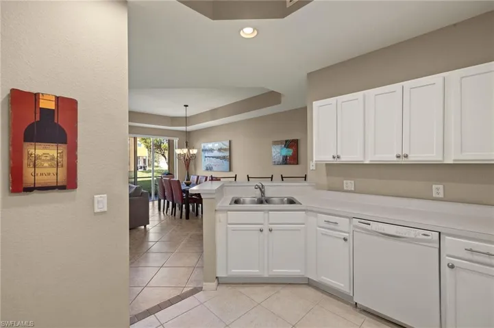 Kitchen with white cabinetry, white dishwasher, kitchen peninsula, and sink