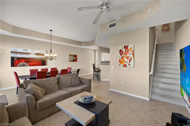 Living room featuring light tile patterned flooring and ceiling fan with notable chandelier