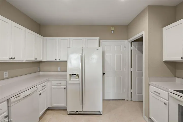 Kitchen with light tile patterned floors, white cabinets, and white appliances