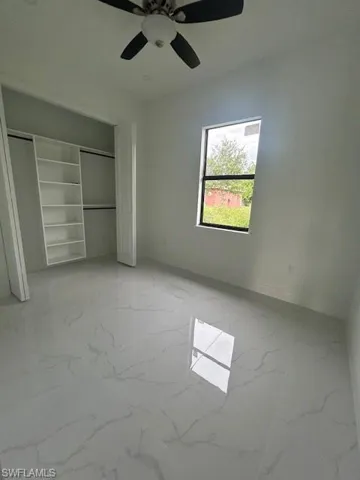 Unfurnished bedroom featuring light marble finish floors, a closet, and ceiling fan
