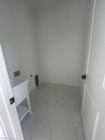 Laundry room featuring light marble finish flooring