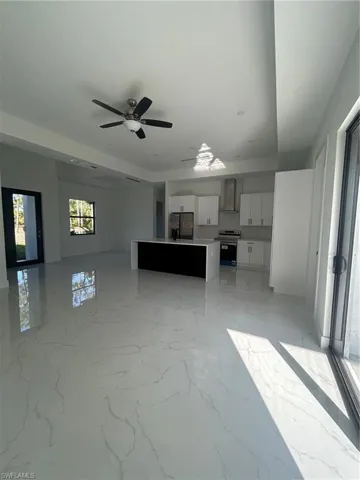 Unfurnished living room with light marble finish floors and a ceiling fan