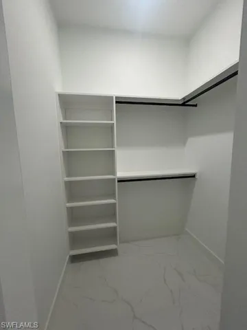 Walk in closet featuring light marble finish flooring