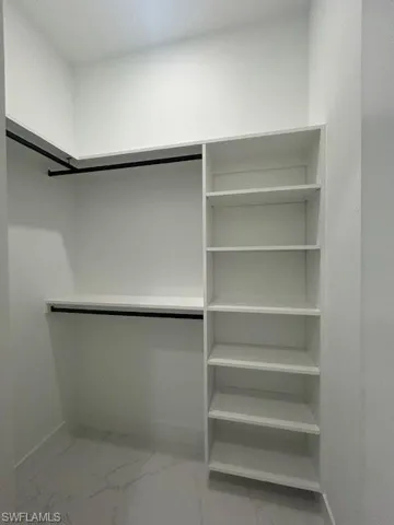 Spacious closet featuring light marble finish flooring