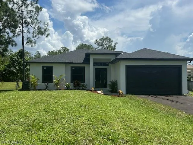 Prairie-style house with a front lawn, stucco siding, driveway, and an attached garage