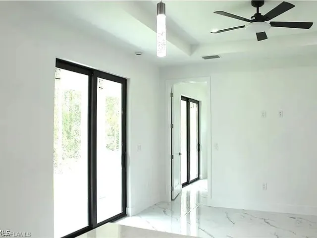 Bright interior space featuring large sliding glass doors, white walls, and polished white tile flooring