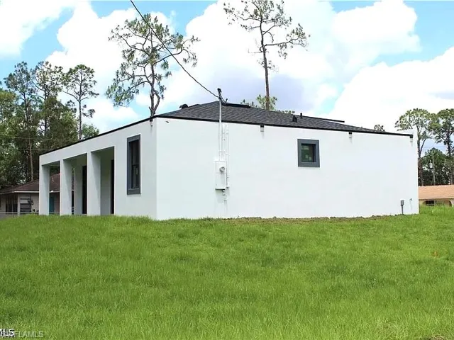 Contemporary exterior with a stark white facade, dark-framed windows, and a black shingle roof