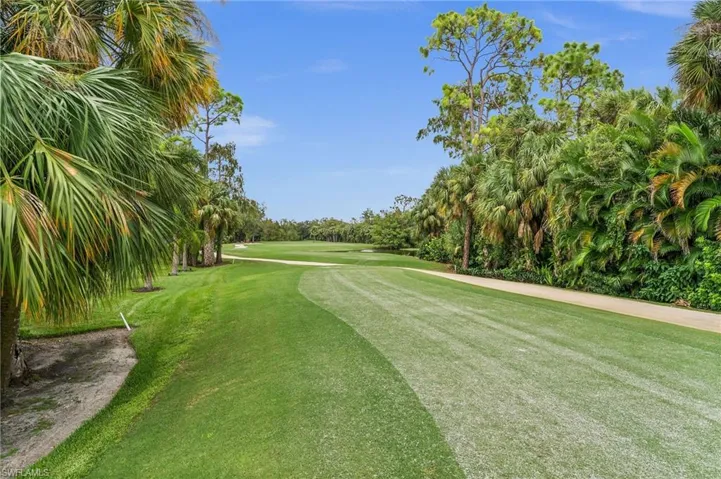 Surrounding community featuring view of wooded area, golf course view, and a yard