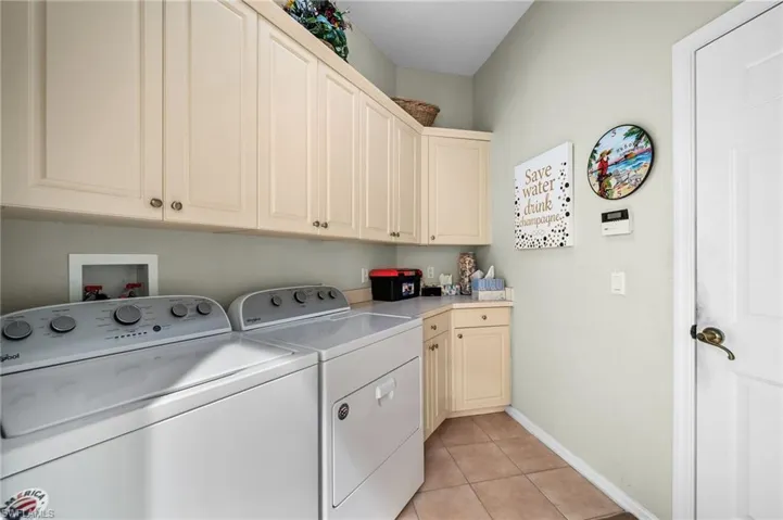 Laundry room with light tile patterned flooring, cabinet space, and washing machine and dryer
