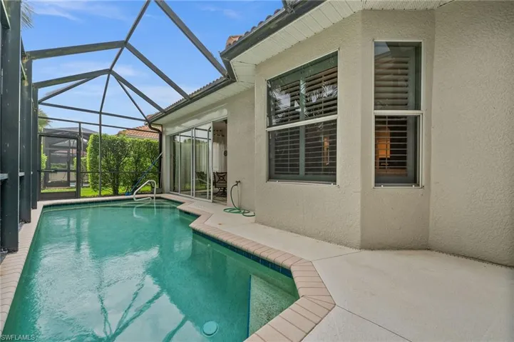Outdoor pool with a patio area, a sunroom, and glass enclosure