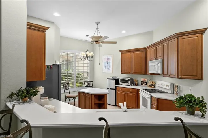 Kitchen with white appliances, brown cabinets, light countertops, hanging light fixtures, and a chandelier