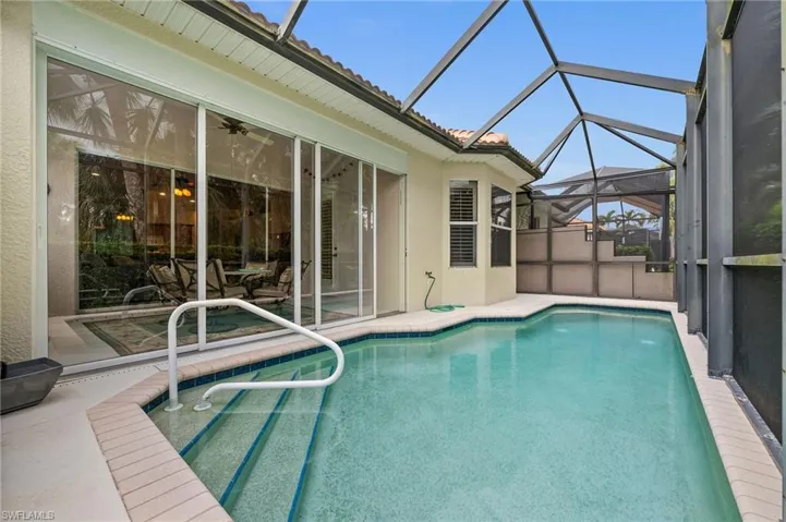 Outdoor pool featuring a sunroom, glass enclosure, and a patio