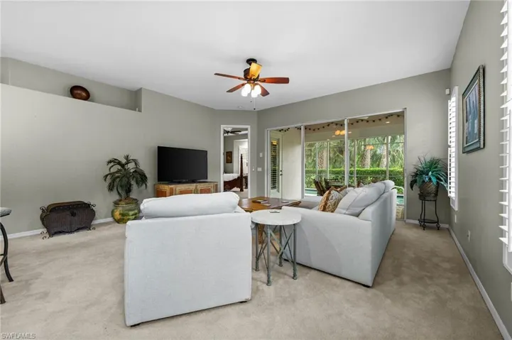 Carpeted living area featuring a ceiling fan and a sunroom