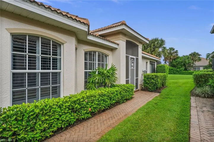 Doorway to property featuring stucco siding, a lawn, and a tiled roof