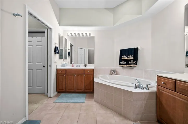 Bathroom featuring a bath, light tile patterned floors, and vanity
