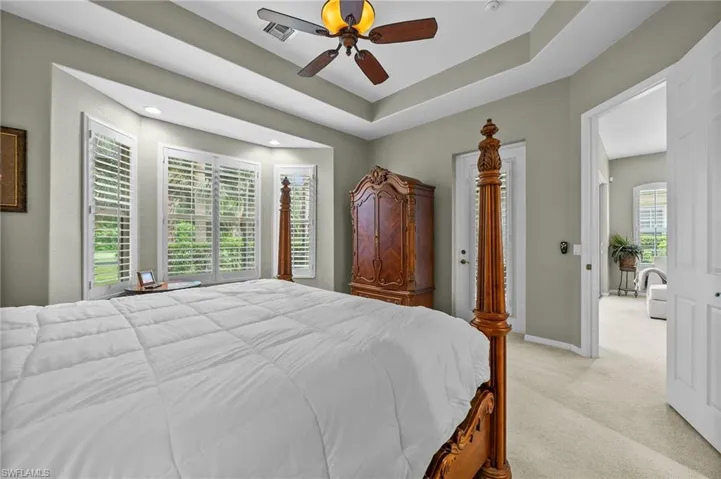 Bedroom featuring light colored carpet, a ceiling fan, and a raised ceiling