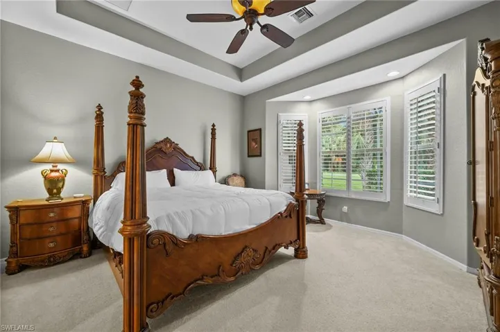 Bedroom with carpet floors, a raised ceiling, and a ceiling fan