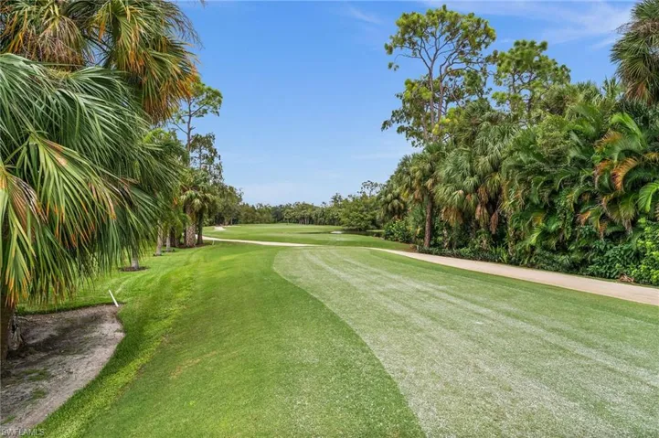 View of home's community with view of wooded area, golf course view, and a lawn