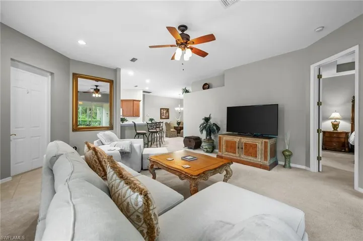 Living room featuring light colored carpet, a ceiling fan, recessed lighting, and a chandelier