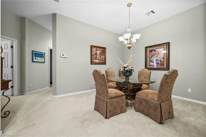 Dining space with light carpet and a chandelier
