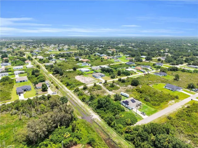 Expansive aerial showcasing a residential area with dispersed single-story homes, surrounded by abundant natural greenery