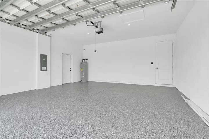 Spacious garage featuring a durable epoxy-coated floor, painted white walls, and an automatic garage door opener system