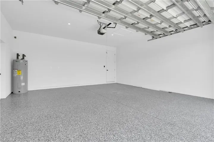 Spacious garage featuring a durable epoxy-coated floor, bright white walls, recessed lighting, and a modern garage door opener mechanism