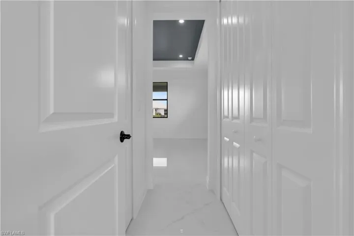 Hallway featuring white paneled doors, white bi-fold closet doors, and white tile flooring