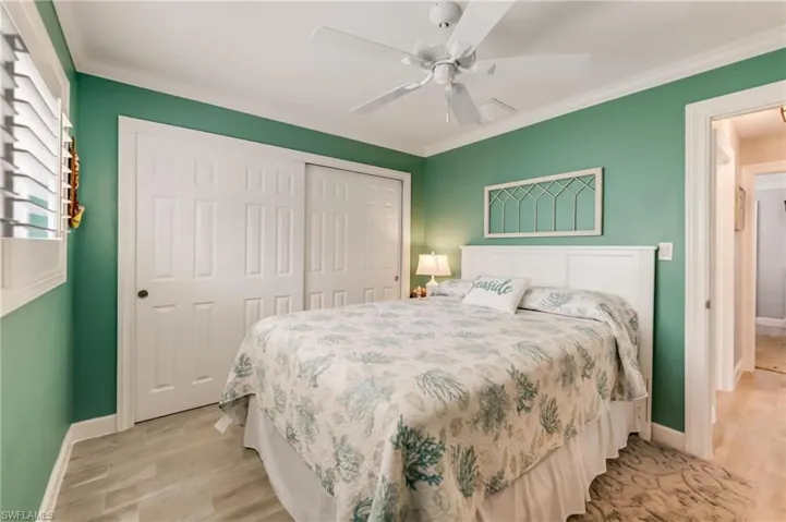 Bedroom featuring light wood finished floors, ornamental molding, and ceiling fan