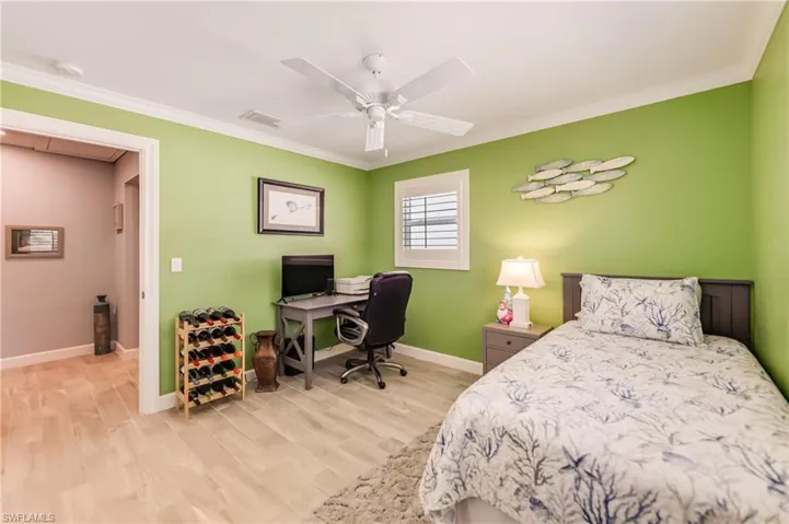 Bedroom with ornamental molding, wood finished floors, and ceiling fan