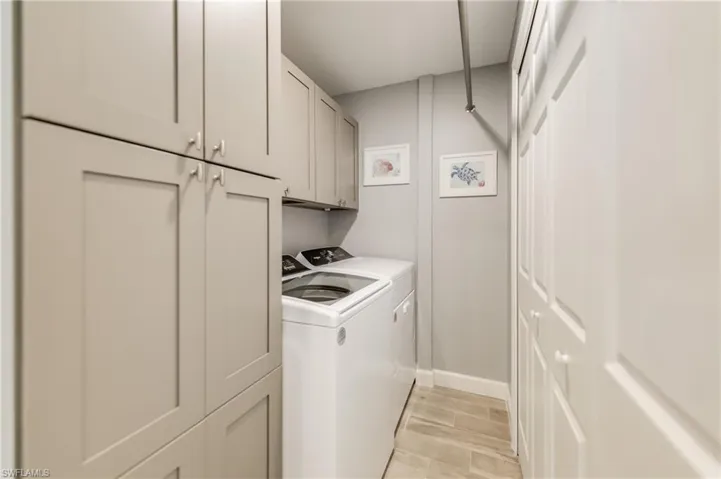 Washroom featuring cabinet space, washing machine and clothes dryer, and light wood-style flooring