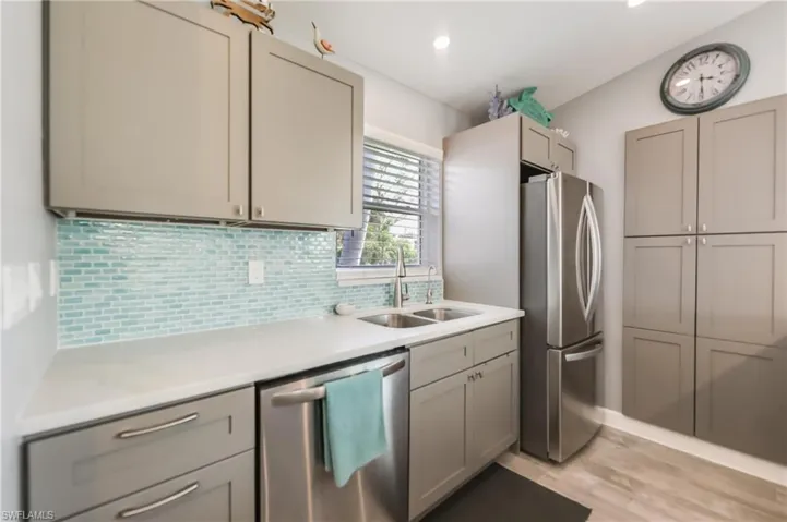Kitchen featuring lofted ceiling, gray cabinetry, a peninsula, light countertops, and decorative backsplash