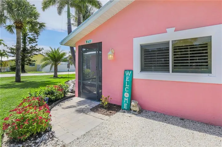 View of exterior entry with stucco siding and a lawn