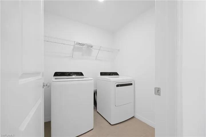 Laundry area with washing machine and dryer and light tile patterned flooring