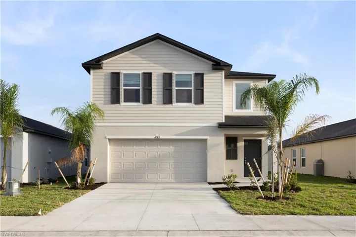 Traditional-style home with concrete driveway, a front yard, an attached garage, and stucco siding