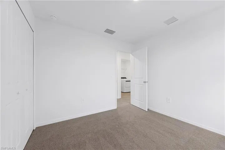 Unfurnished bedroom with dark colored carpet, a closet, and washer / dryer