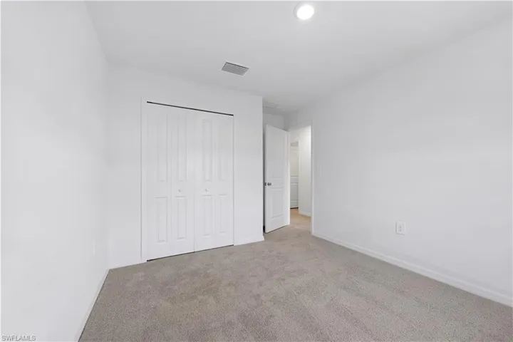 Unfurnished bedroom with light carpet and a closet