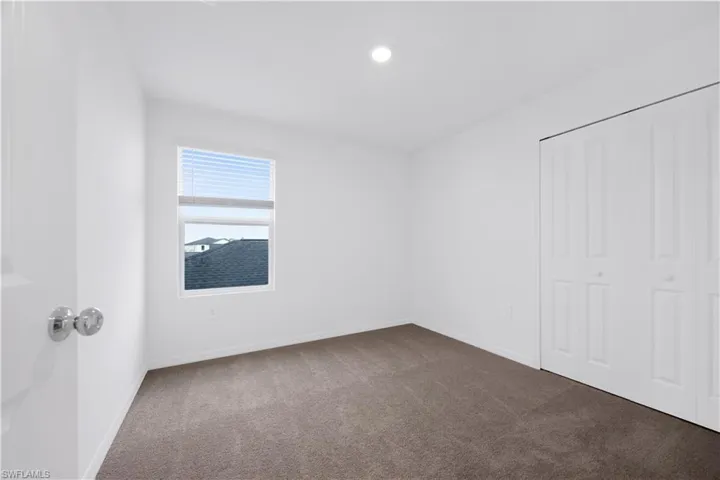 Unfurnished bedroom with dark colored carpet, a closet, and recessed lighting