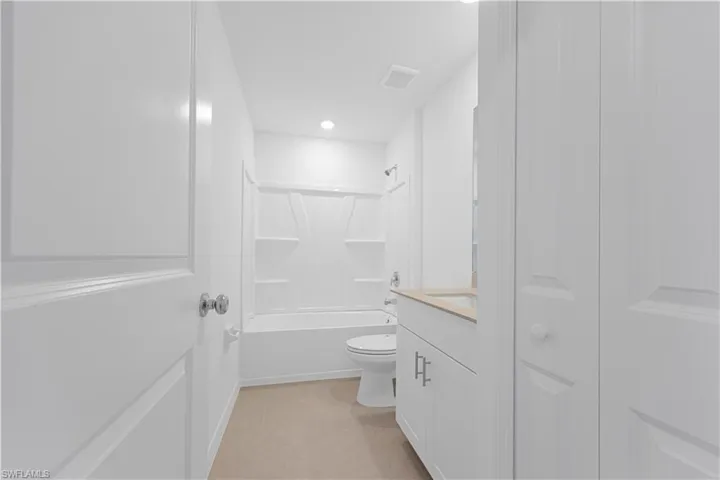 Bathroom featuring vanity, bathtub / shower combination, recessed lighting, light tile patterned flooring, and a closet