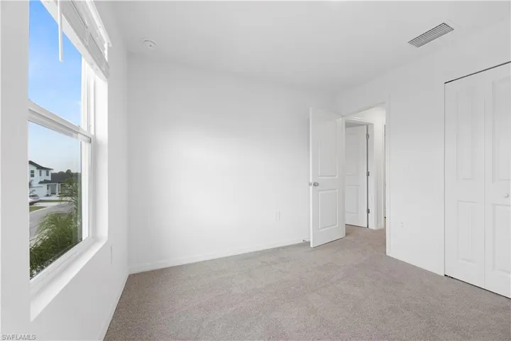 Unfurnished bedroom with light carpet and baseboards
