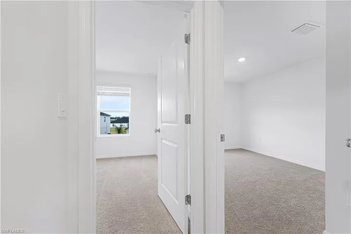 Hallway featuring light colored carpet and recessed lighting