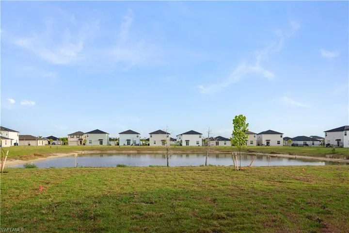 View of green lawn with a residential view and a water view