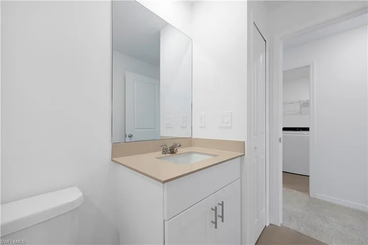 Half bath featuring vanity, washer / dryer, light colored carpet, and a spacious closet
