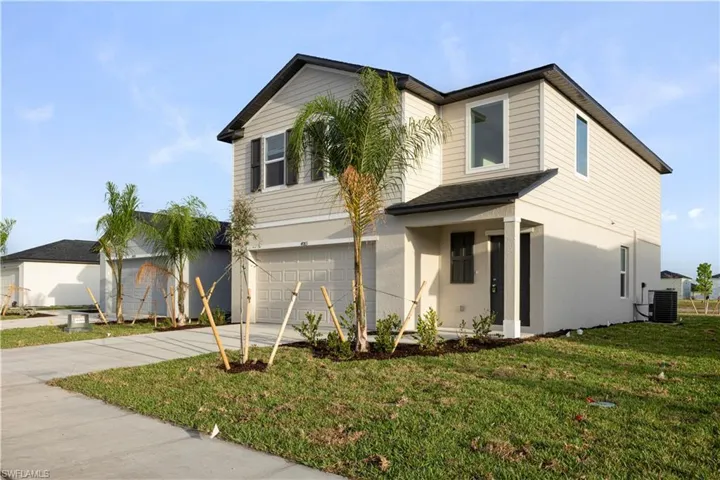 View of front of home featuring driveway, an attached garage, a front lawn, and stucco siding