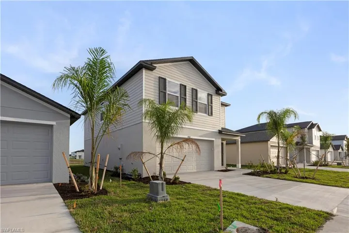 Traditional-style house featuring driveway, a front lawn, an attached garage, and stucco siding