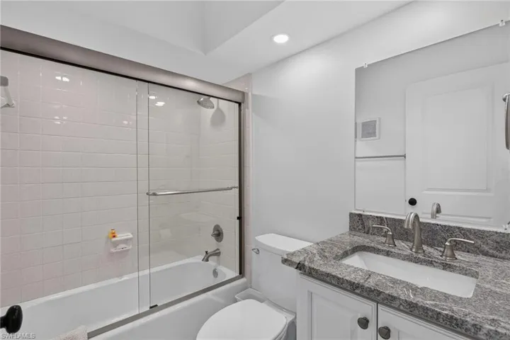 Guest bathroom with new tile, heavy glass doors, vanity, lighting/plumbing fixtures.